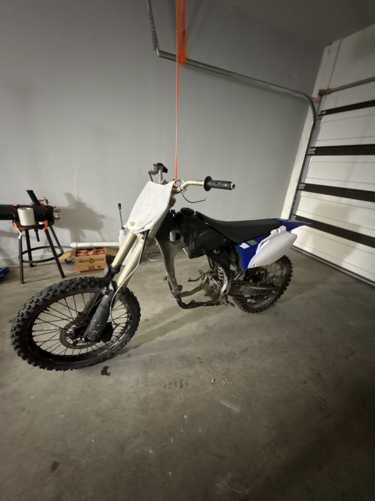The engineless 2006 Yamaha YZ450F rolling chassis in a garage