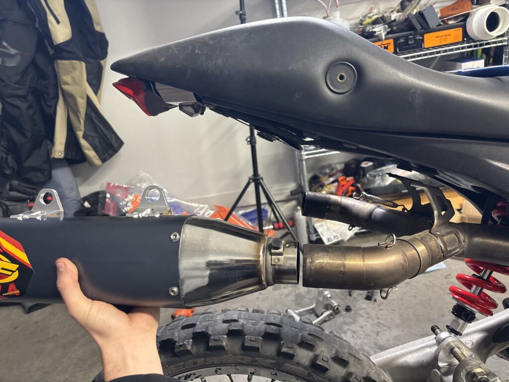 Holding an FMF muffler under the Ducati tail on the right side